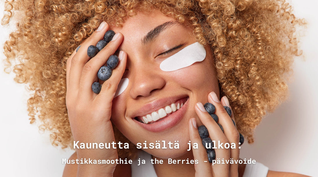 Onnellinen nainen jonka käsissä on mustikoita. Kädet ovat kasvoilla. Nainen hymyilee ja hänellä on silmänalusnaamiot.