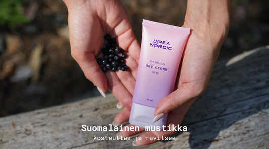 Kädet, jotka pitävät suomalaisia mustikoita sekä päivävoidetta käsissä.